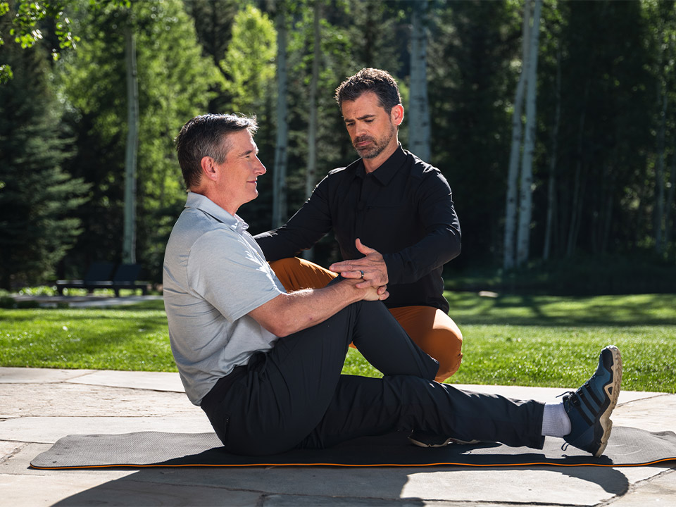 man with his trainer helping to stretch his glutes fitforever online personalized fitness programs