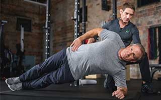trainer helps client with Side Plank fitforever online personalized fitness programs